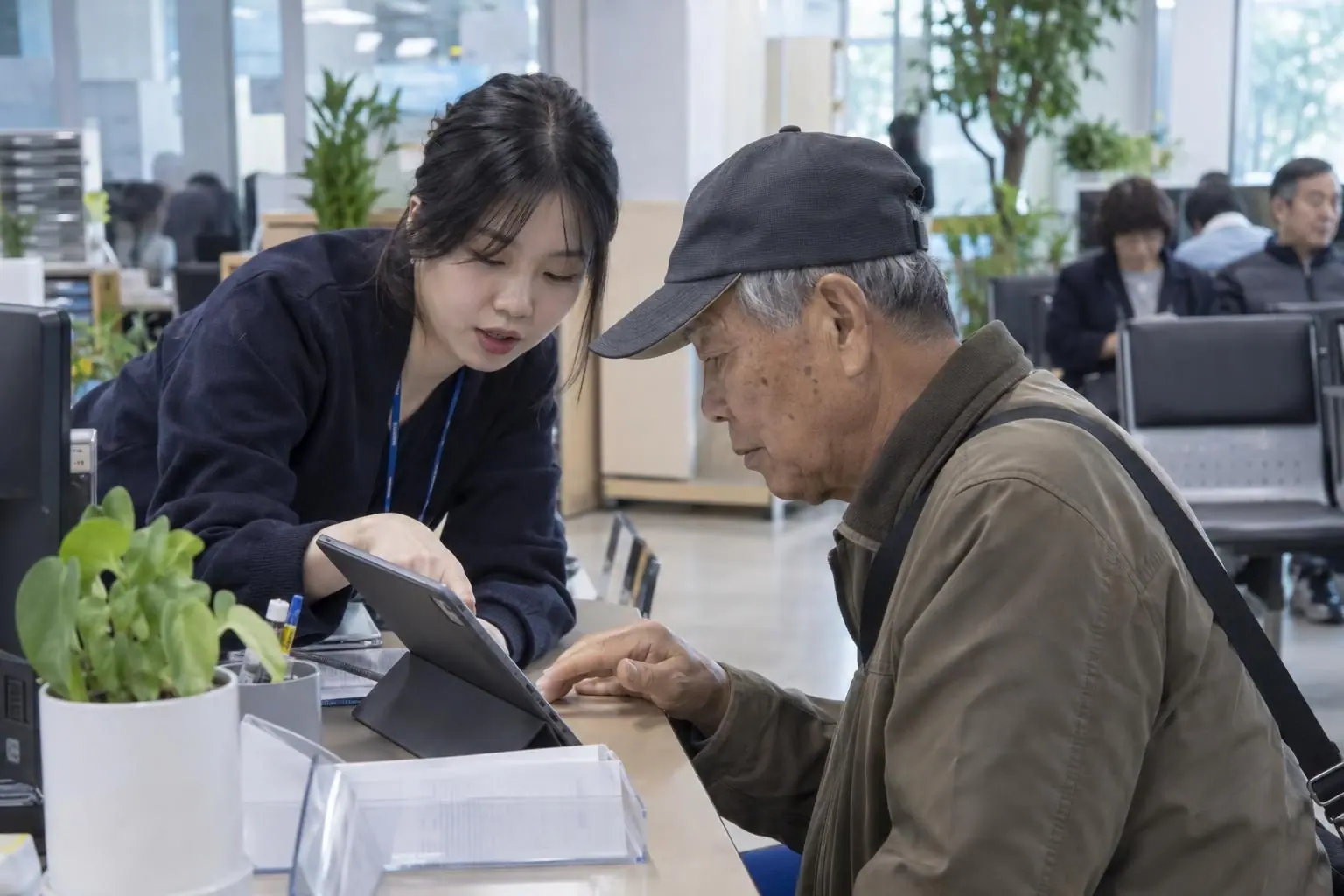 주민센터 직원이 어르신께 태블릿으로 안내하는 모습